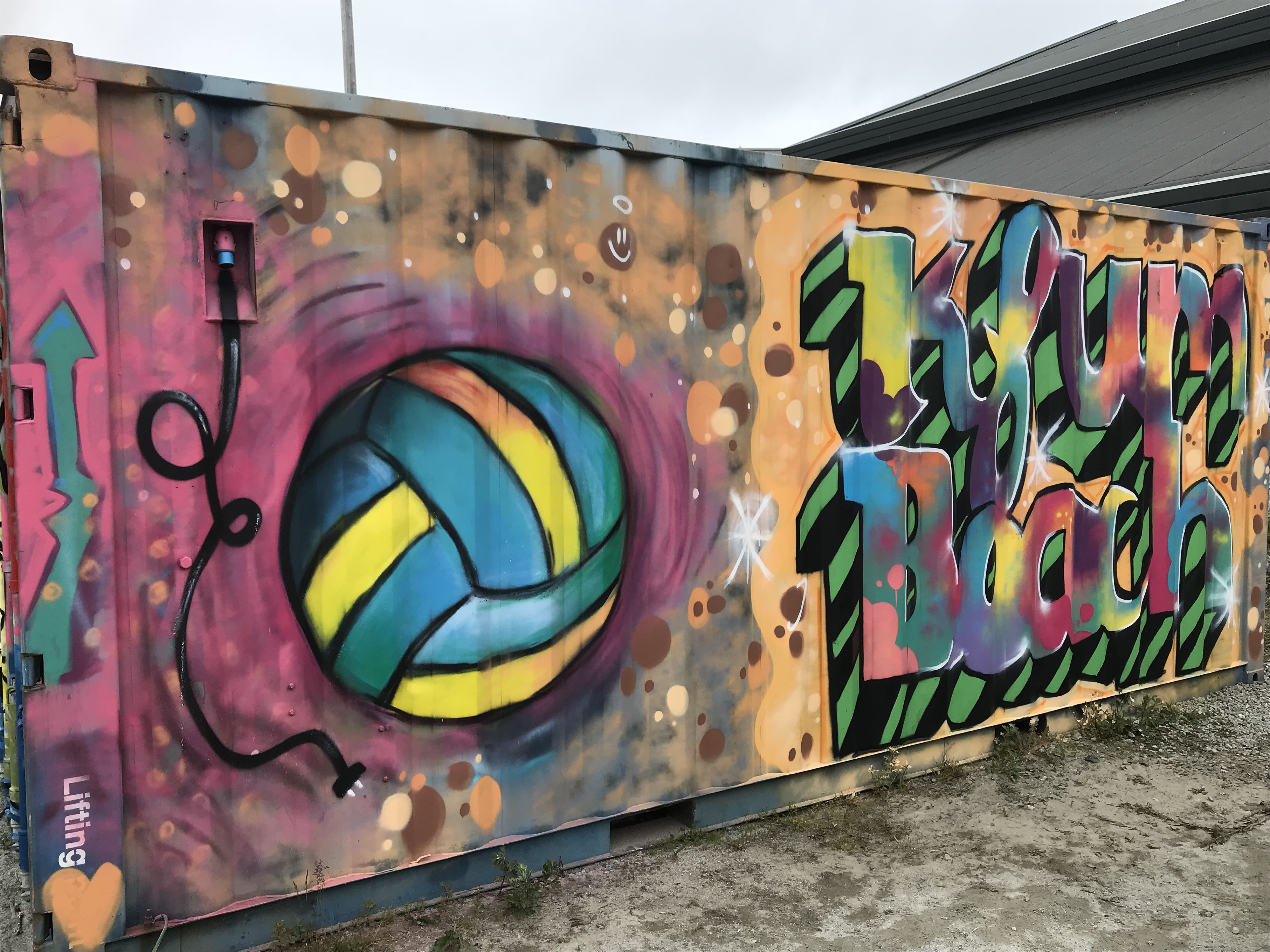 Kontainervegg med street art. En tegning av en volleyball med teksten "kfum beach"